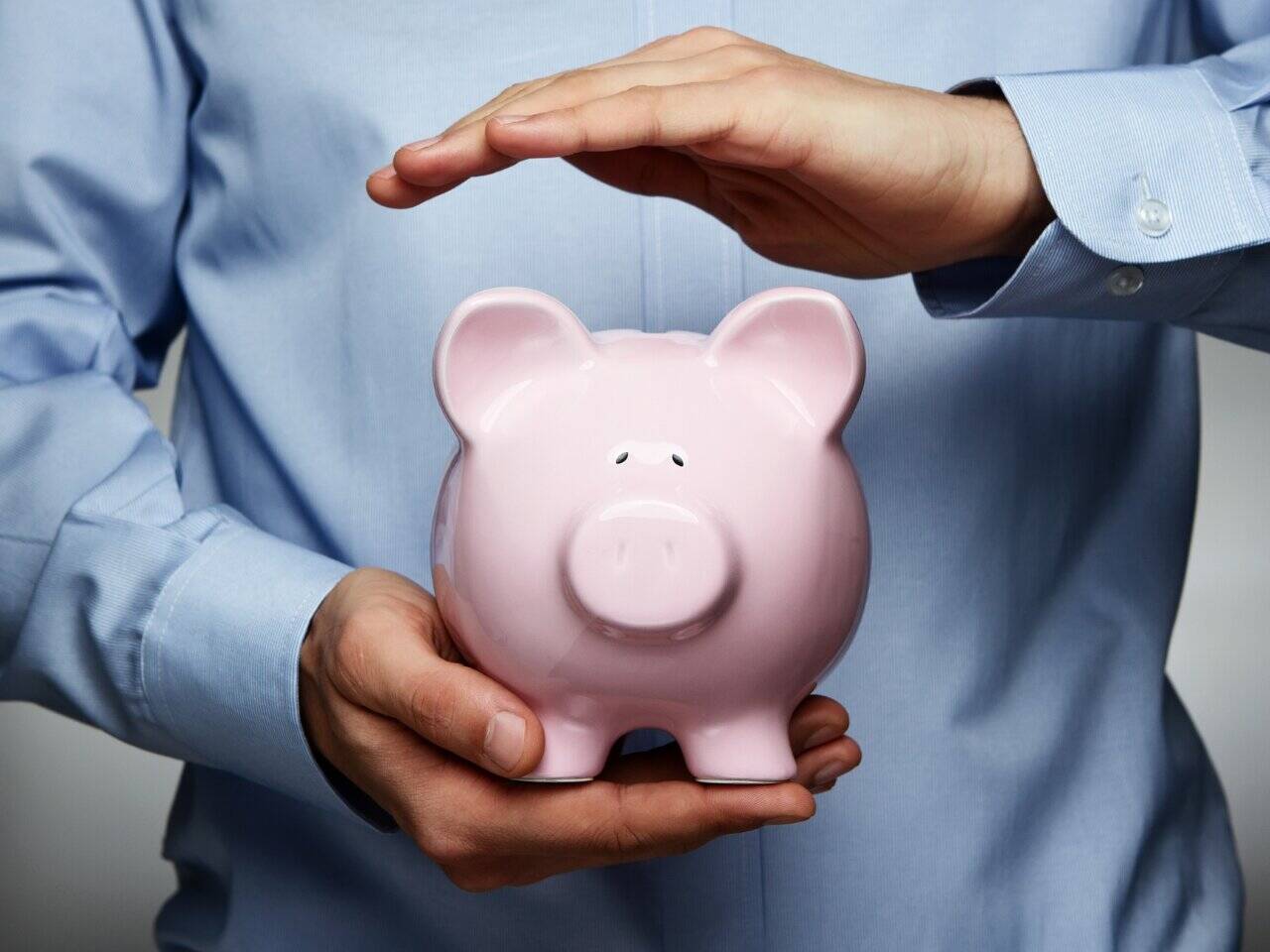 Man protecting a piggy bank. Netvesco Fee-Only Concept.