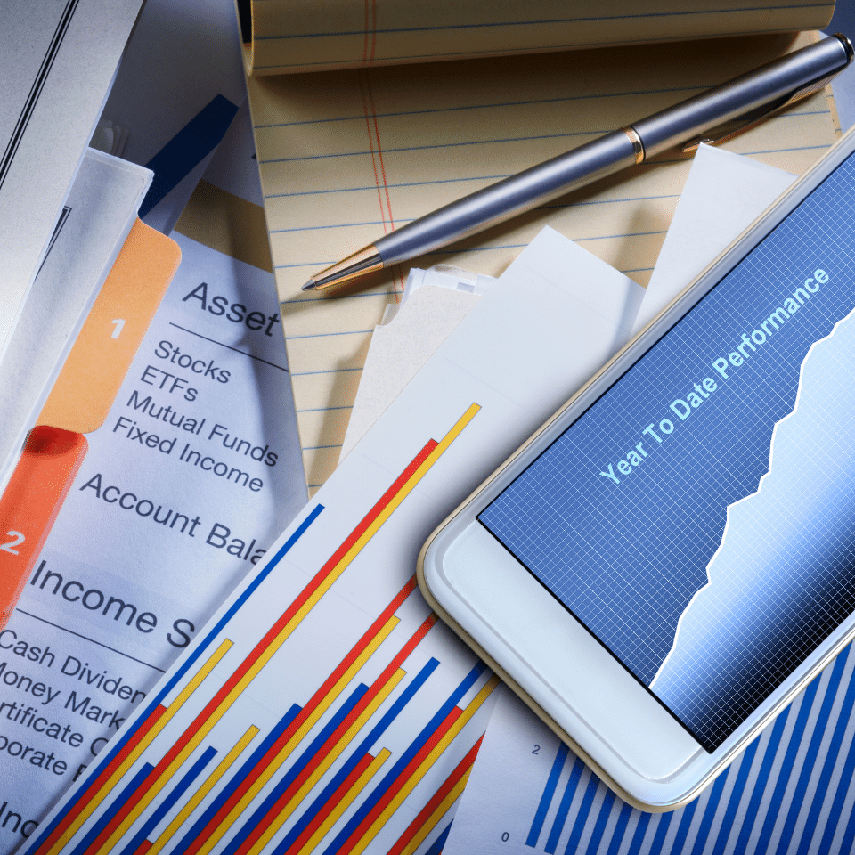 Financial Plan: A bound financial plan sits on a desktop ready for review and analysis. A mobile device and various charts frame the document that has been prepared by a Netvesco financial planner.