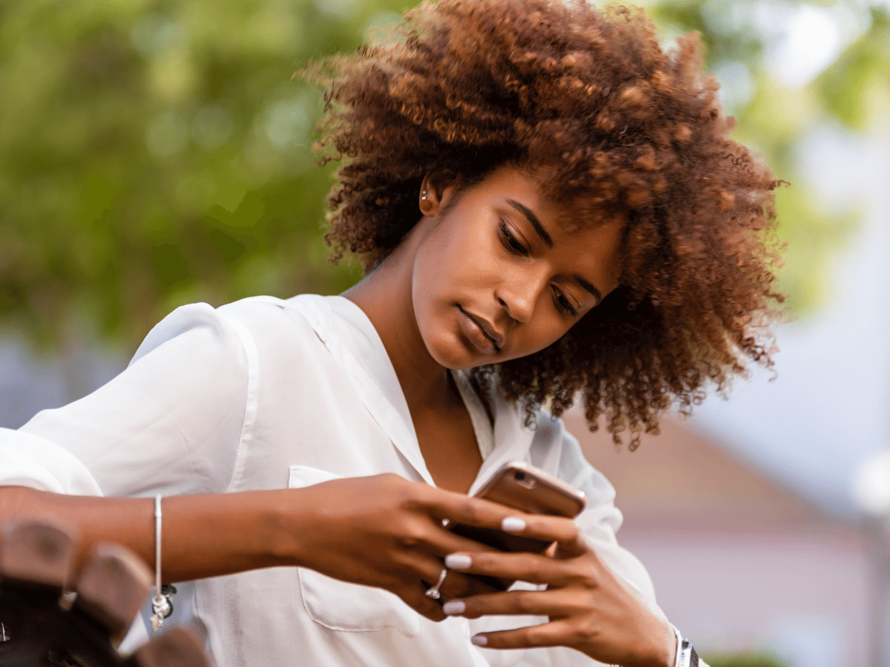 Outdoor portrait of a young Black woman speaking on mobile phone. Contact Concept