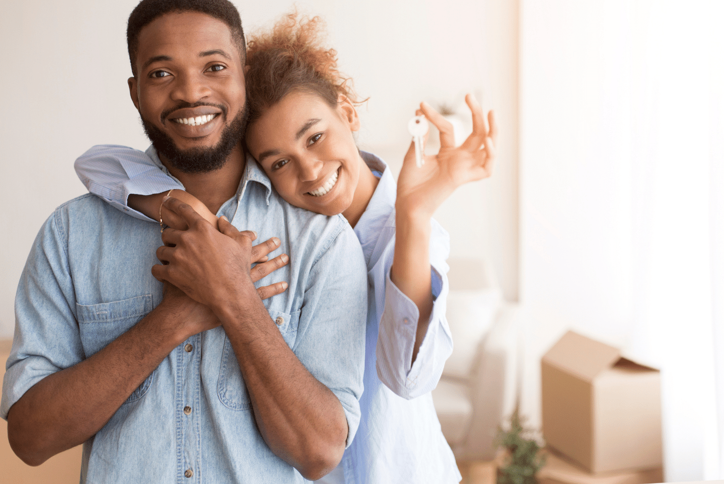 Couple Holding New Home Key; Hugging; Standing In Own House. Ownership Concept.