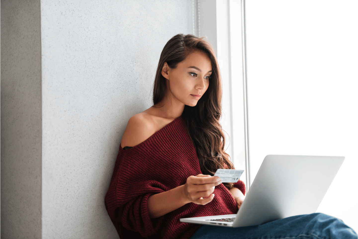 Young beautiful Asian woman holding a credit card and looking at her laptop screen. Personal Finance Concept