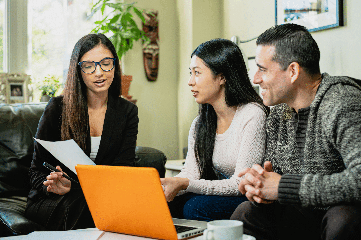 Woman financial advisor talking to couple in the living room of their home.