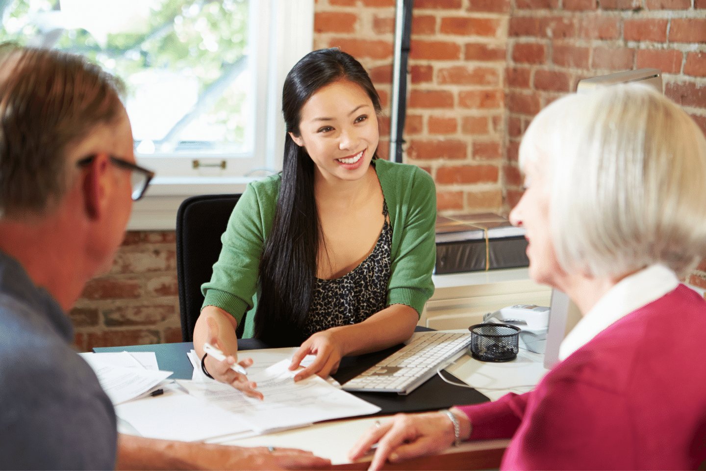 Senior couple meeting with happy smiling Asian financial advisor in office. Investment Planning Concept